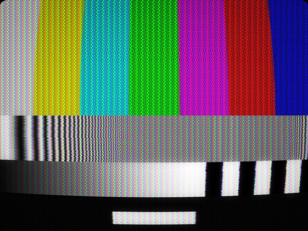 Broadcast NTSC on a shadow-mask tube: dot crawl over the bars, the frequency sweep dying where the luma filter runs out and turning to rainbows where it crosses the subcarrier, halation around the caption.